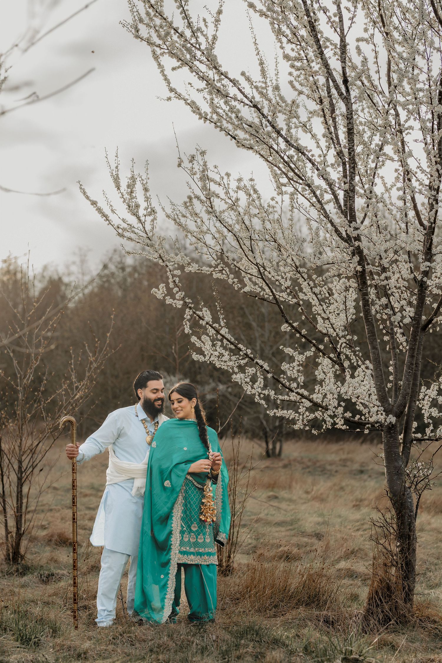 Spring photoshoot featuring a couple among blooming white cherry blossom trees.