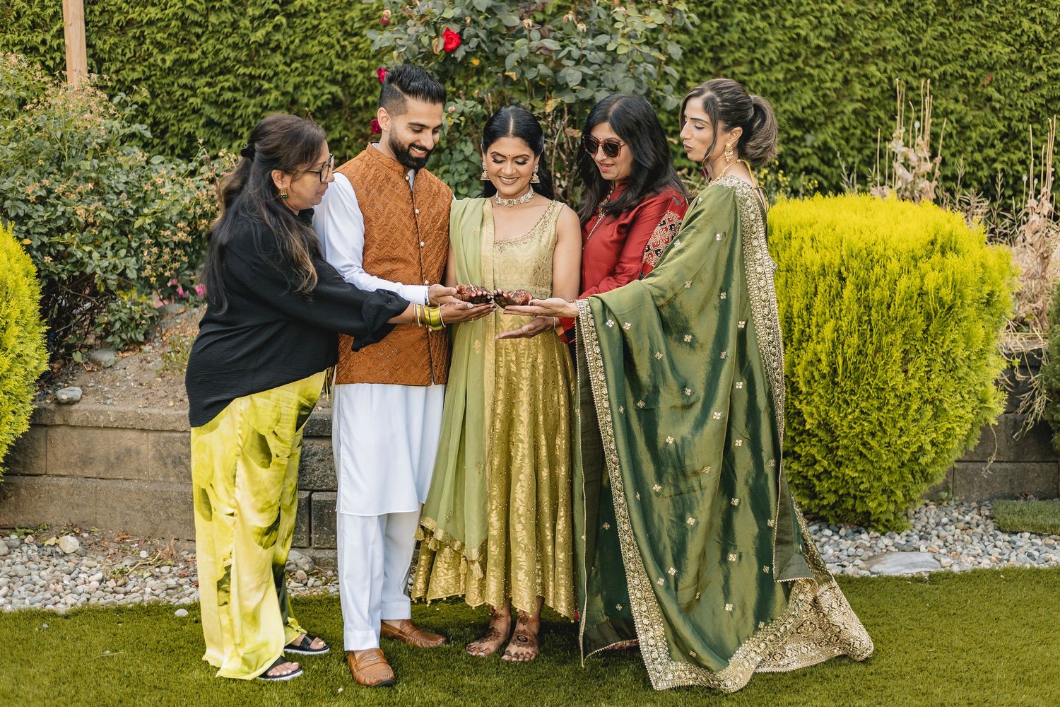 Celebratory gathering in a garden with people wearing colorful traditional South Asian outfits.