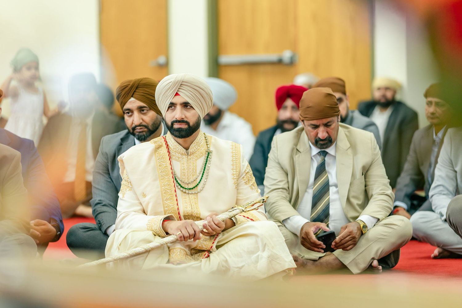 Wedding guests in traditional Punjabi attire seated during ceremony.