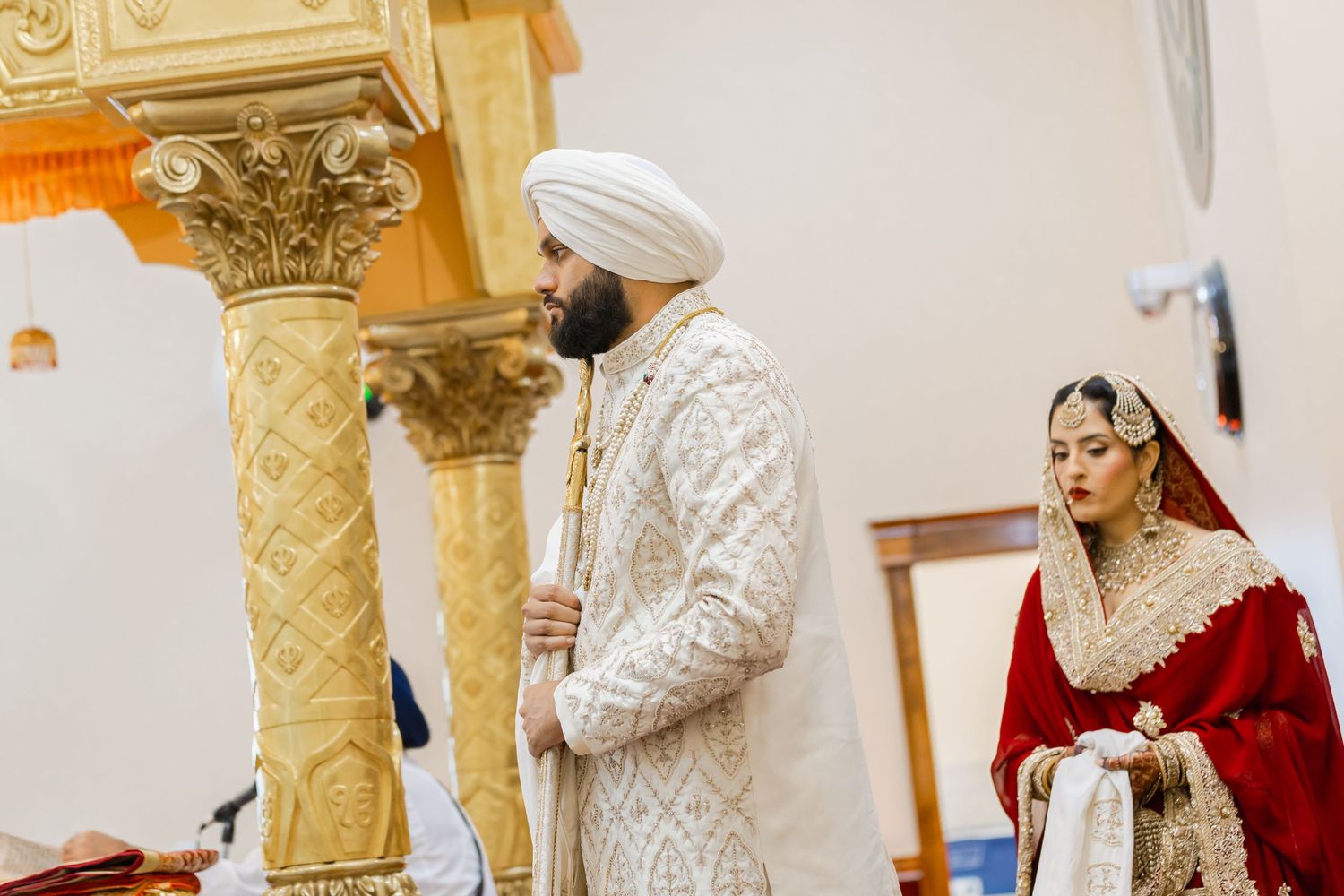 Traditional wedding ceremony with ornate gold pillars and decorative elements.
