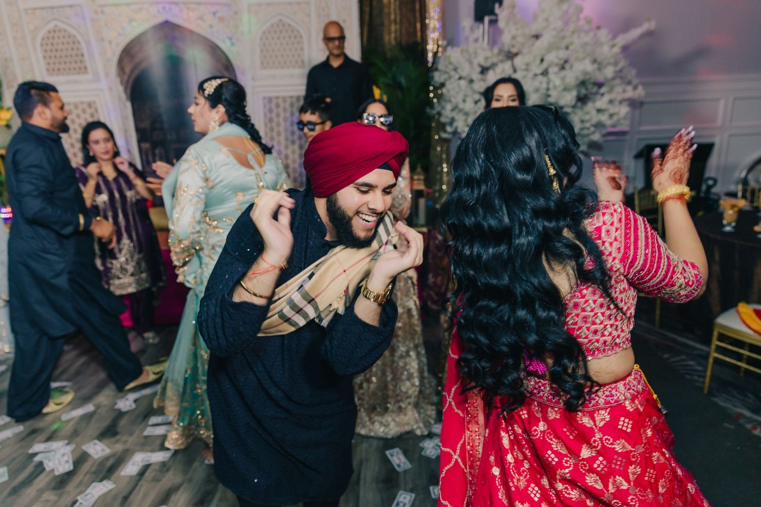 Guests dancing and celebrating at an Indian wedding reception with ambient lighting.