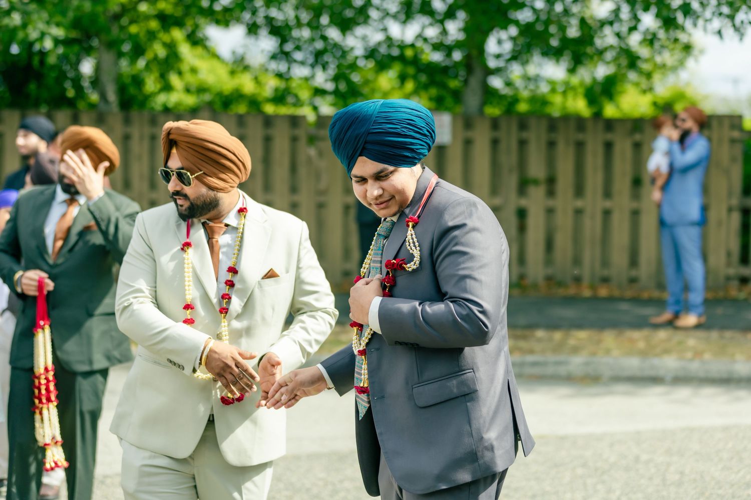 Guests in traditional formal attire gather outdoors during a celebration.