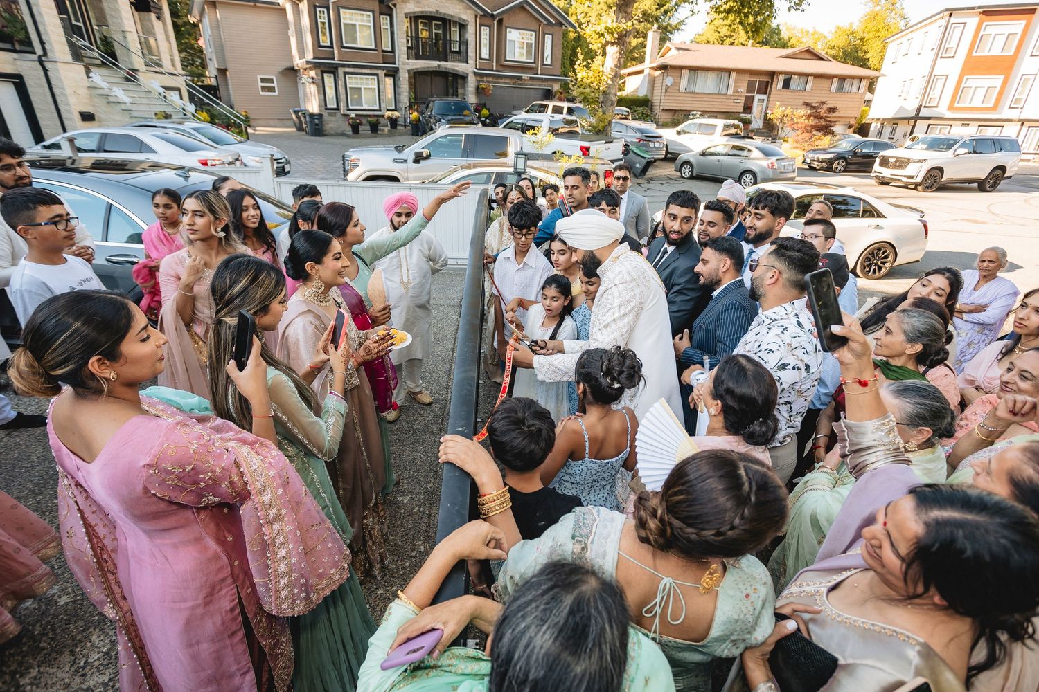 Wedding guests with phones and cameras capturing moments during an outdoor celebration.