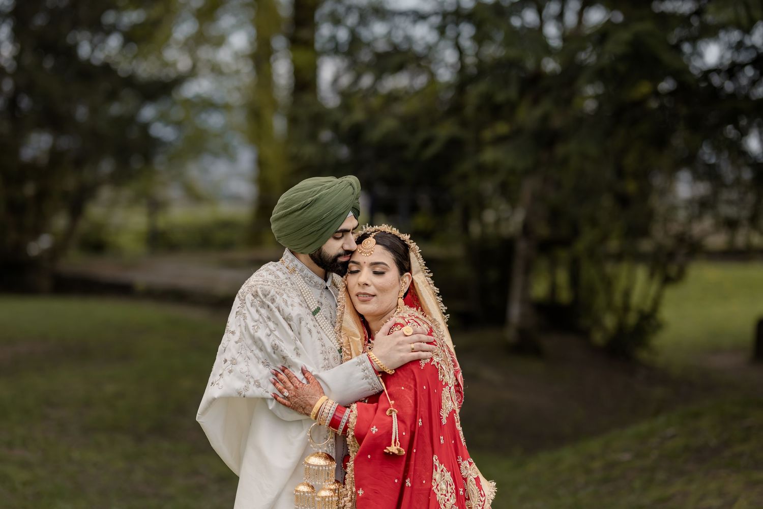 A romantic outdoor photo session with traditional Indian wedding attire in a lush green setting.