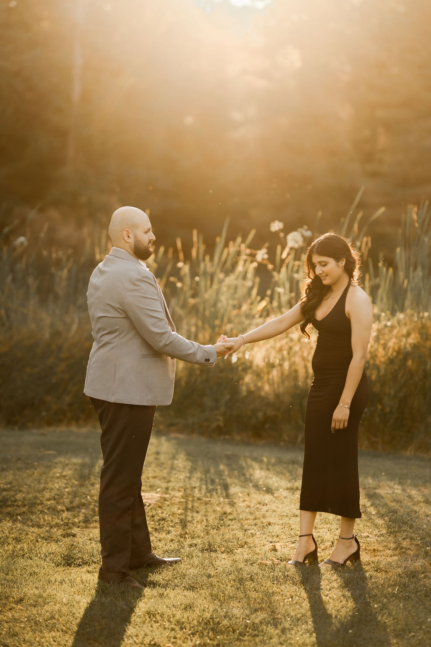 Two people sharing a romantic moment in a sunlit meadow during golden hour.