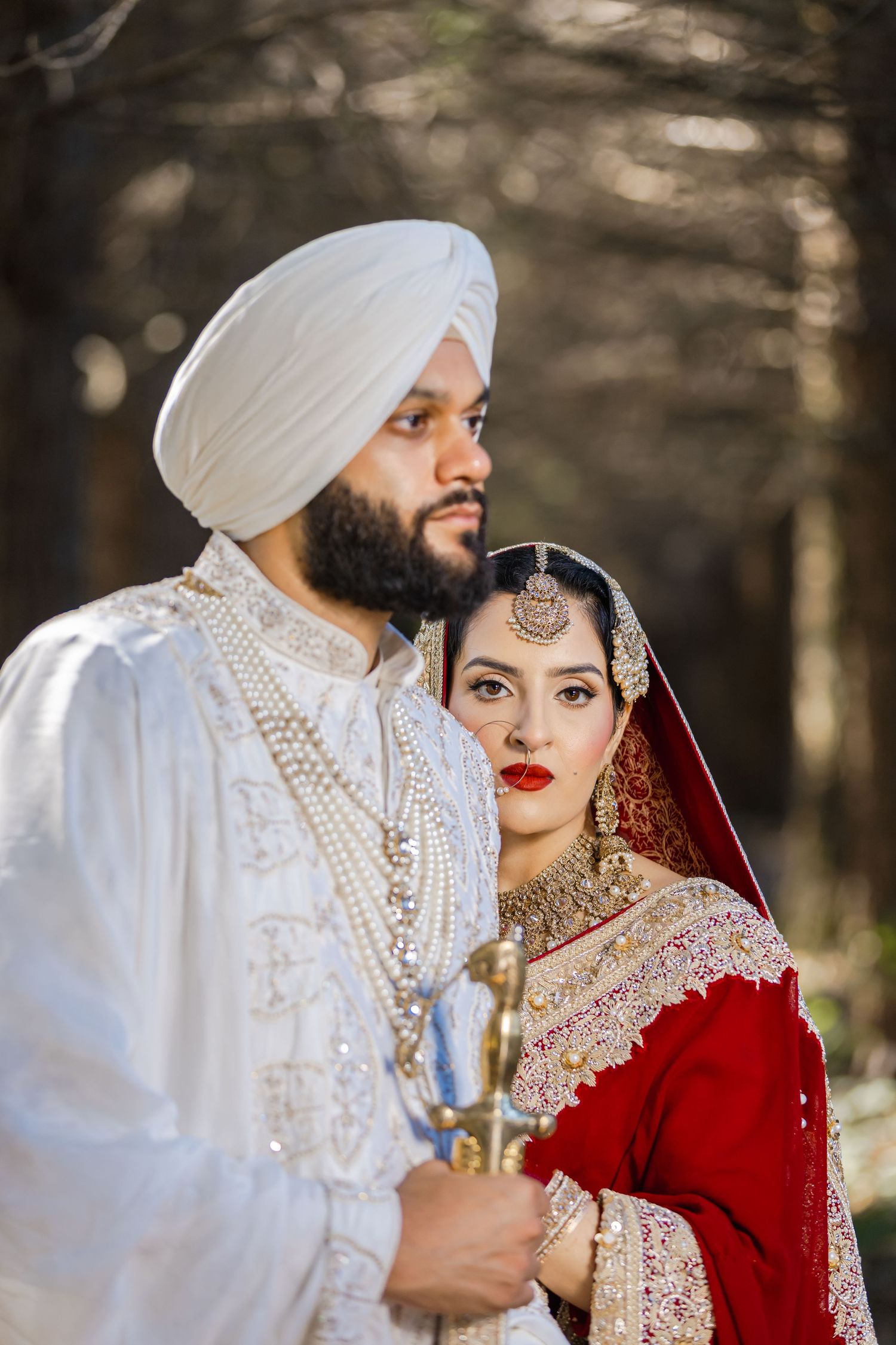 Traditional Sikh wedding ceremony outdoors with couple in ornate red and white wedding attire.