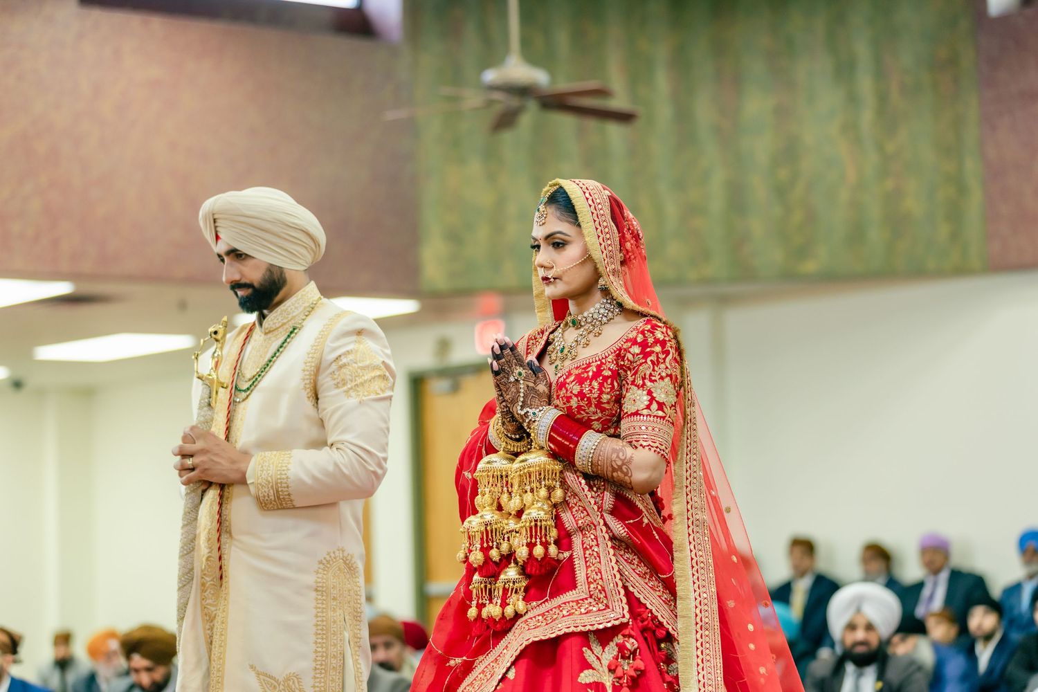 Traditional Sikh wedding ceremony with guests seated on red carpet.