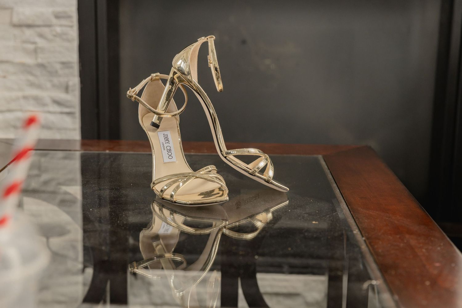 Gold metallic sandals displayed on a dark wooden surface.