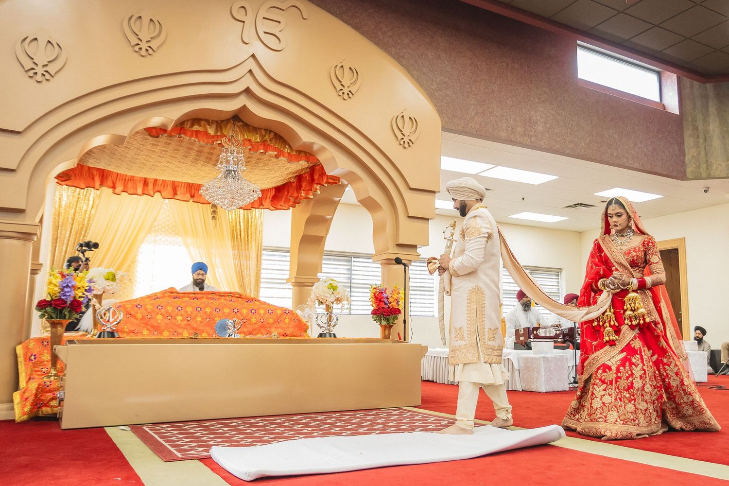 A traditional Indian wedding ceremony setup with red carpet and elegant architectural details.