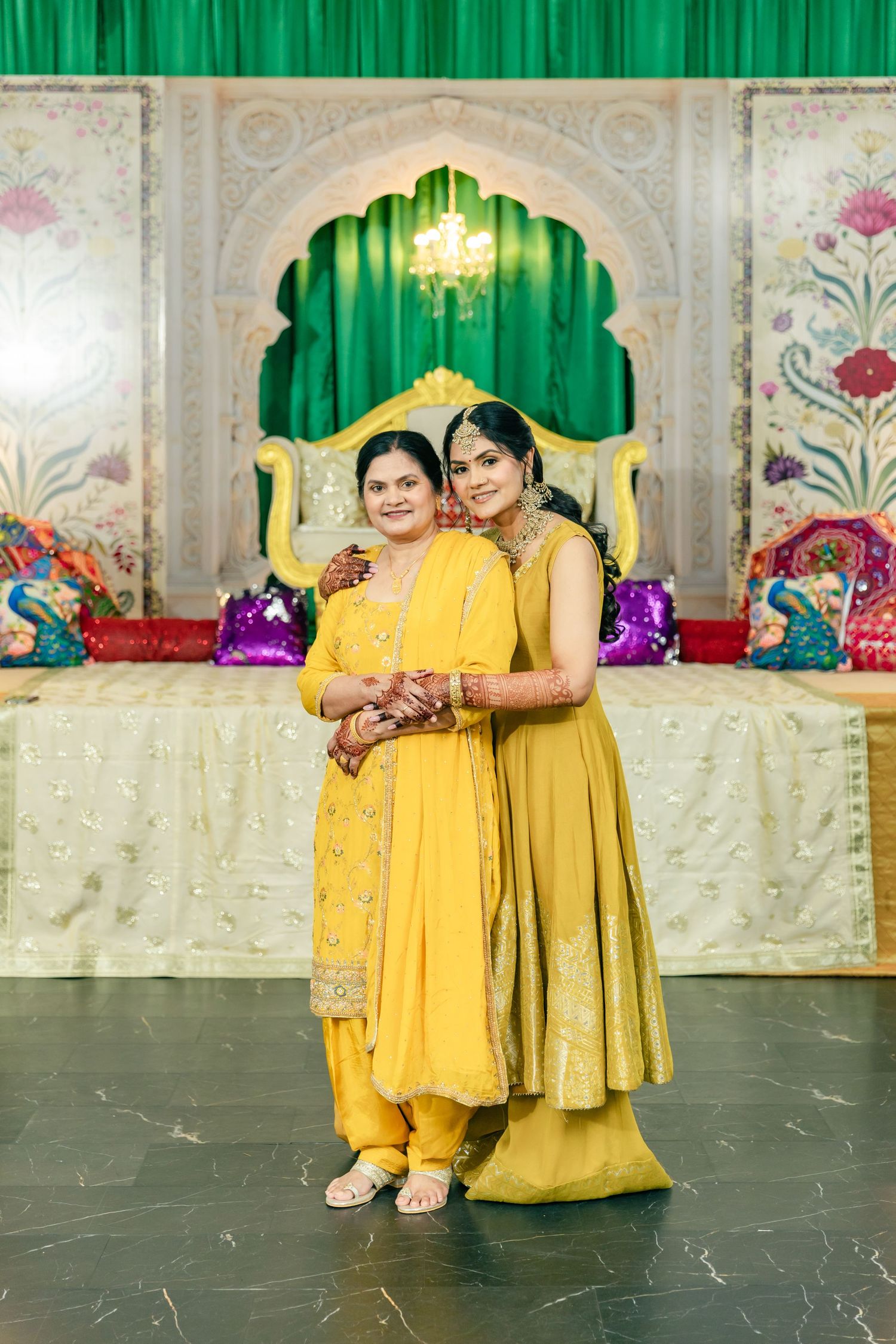 Group wearing yellow and gold outfits posing in front of decorative green and white backdrop.