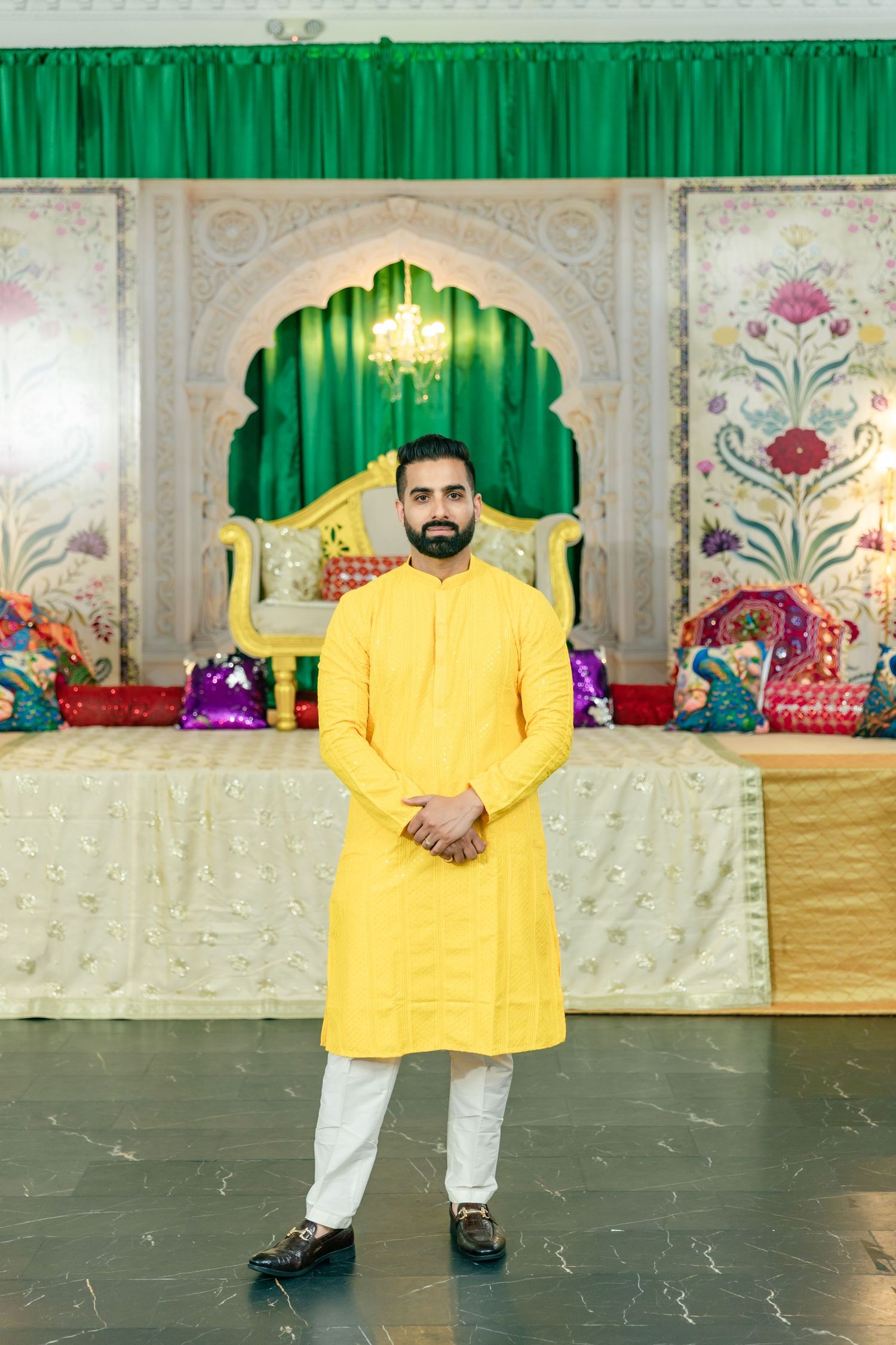 Festive indoor venue decorated with green curtains and ornate details featuring yellow and white decor elements.