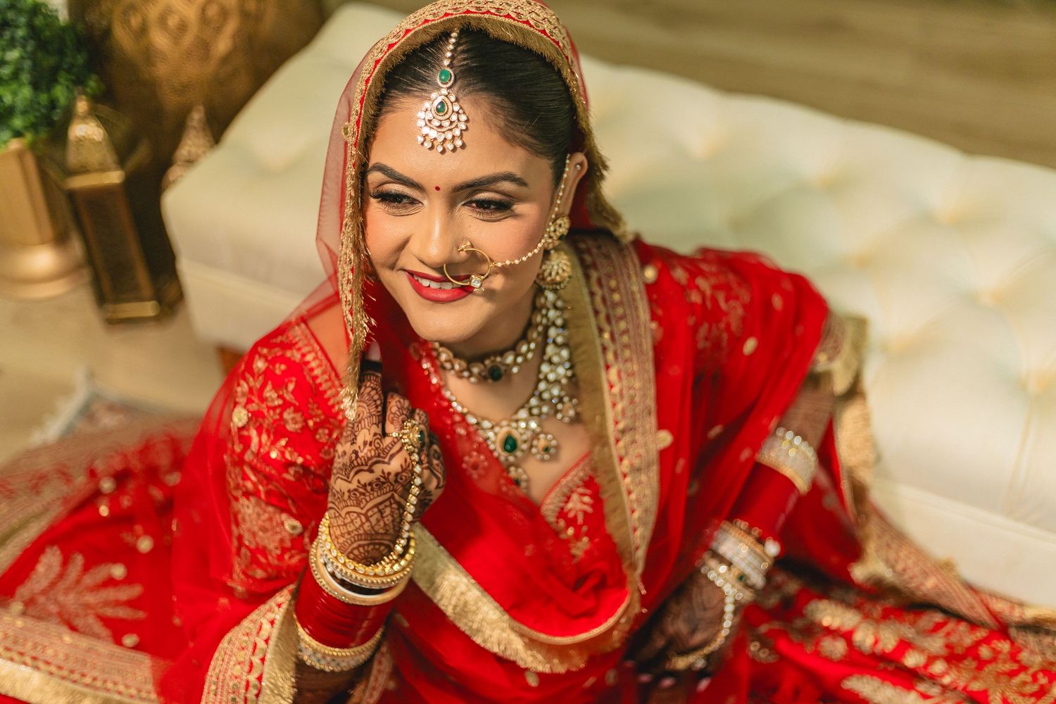 Traditional Indian bride in elegant red bridal lehenga with detailed embroidery and jewelry.