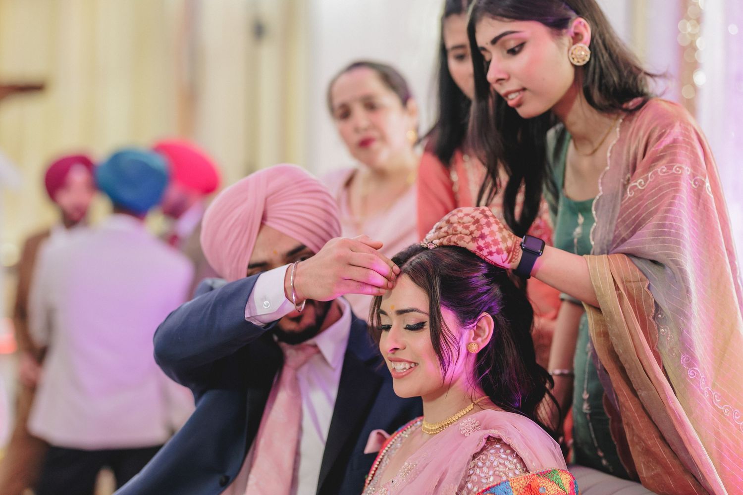 Traditional Indian wedding preparation ceremony showing detailed hair styling in pink and gold decor.