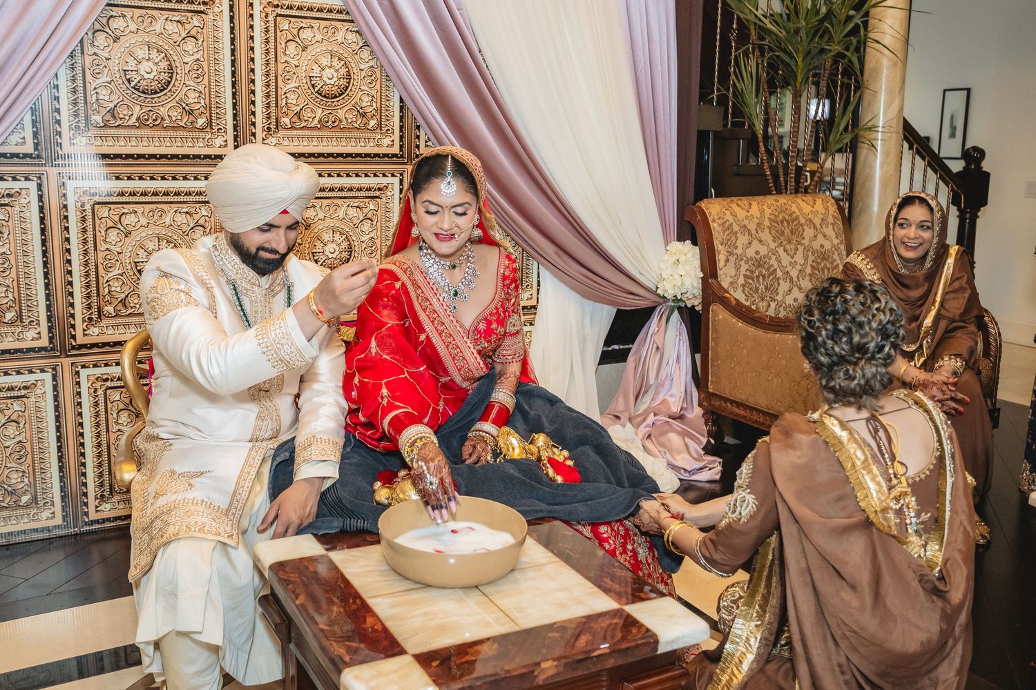 Traditional Indian wedding ceremony with ornate decorations and guests seated indoors.