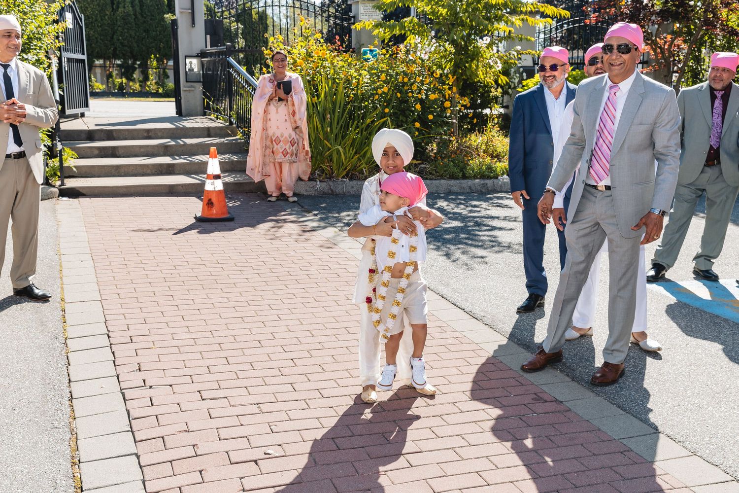 Wedding guests walking outside on a sunny day along a stone pathway.