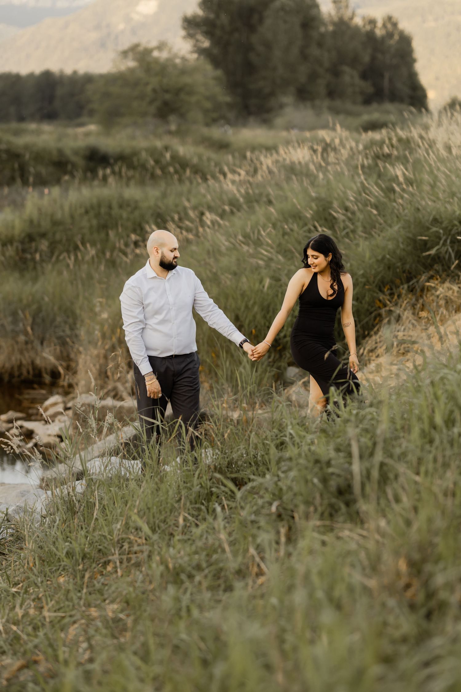 A couple explores a scenic trail through tall grass during golden hour.