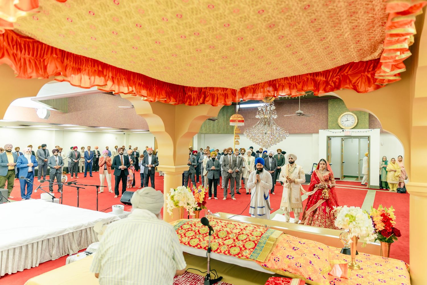 Panoramic view of an elegant wedding hall decorated with red and gold drapes and ornate details.