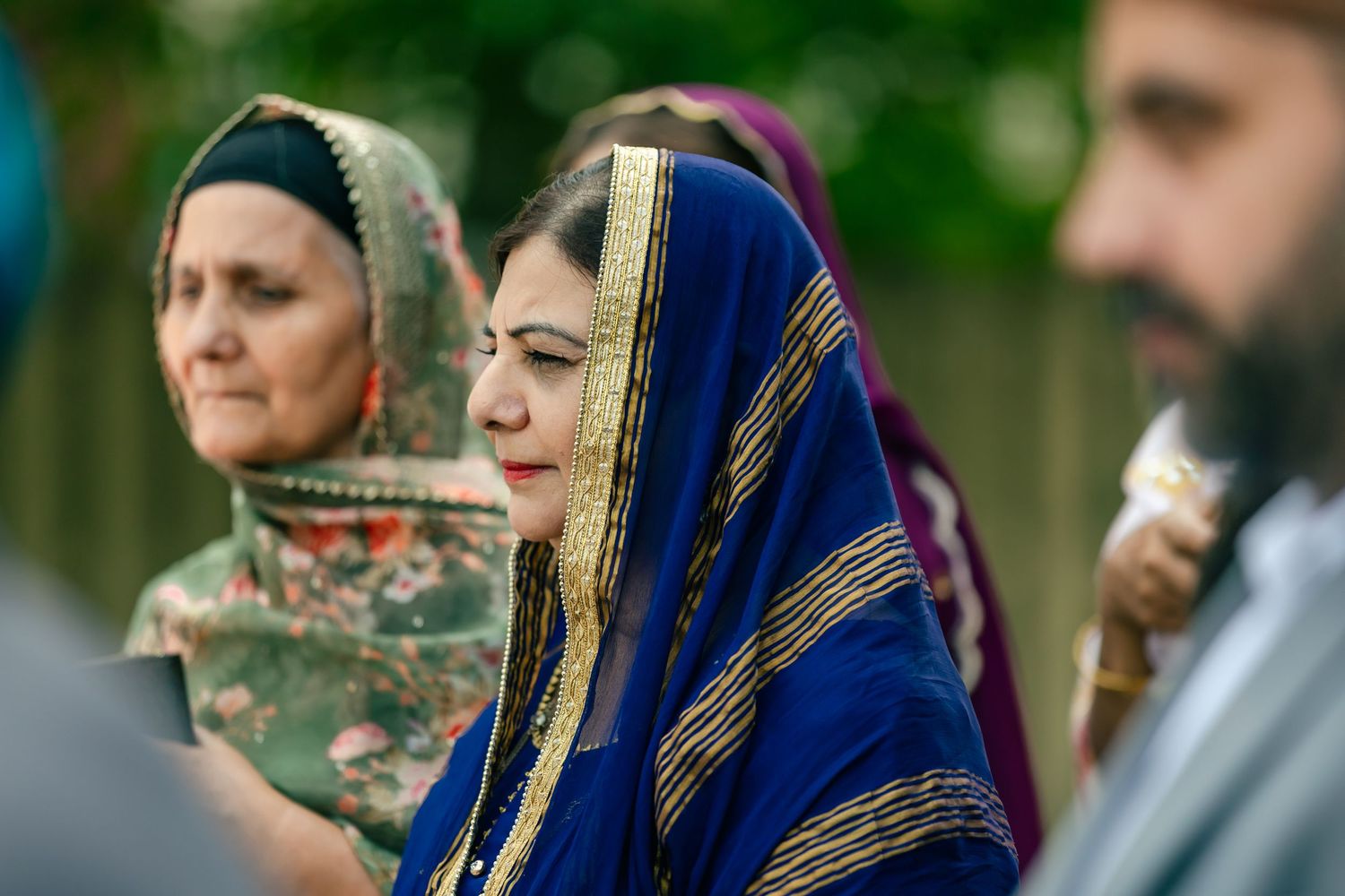 Guests in traditional attire observing a cultural wedding ceremony outdoors.