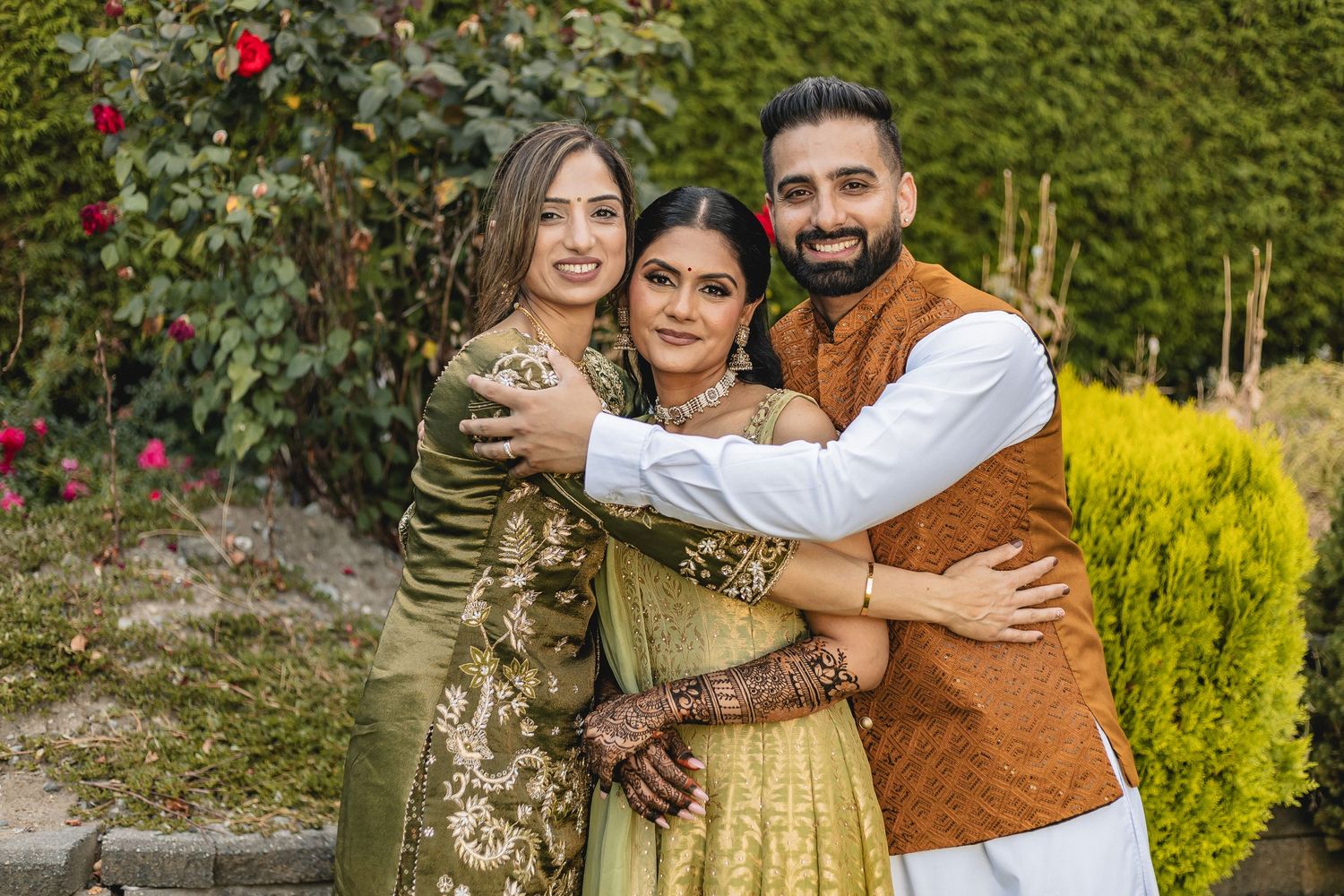 Family group poses together in garden setting wearing traditional South Asian clothing.