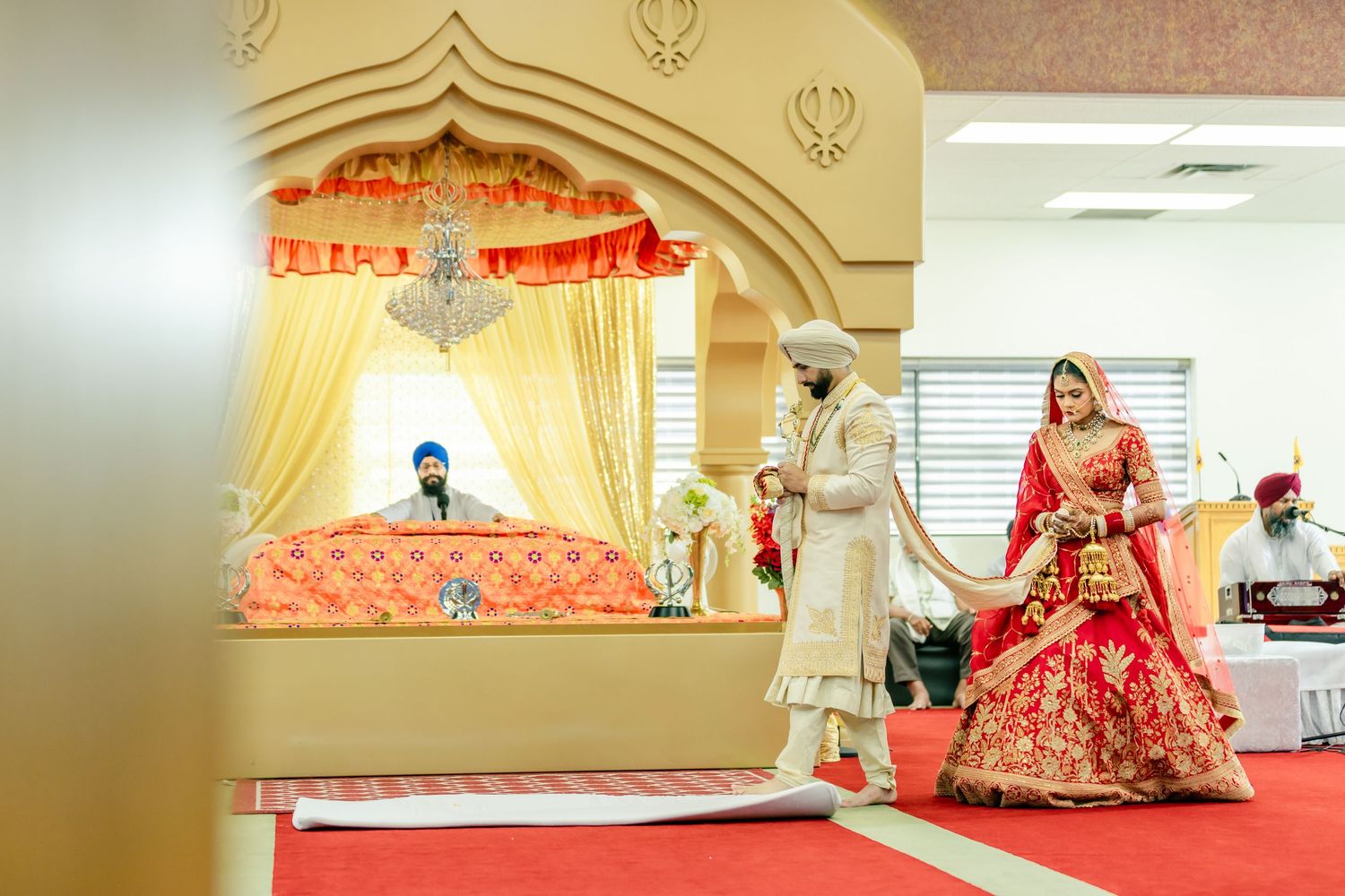 Wedding ceremony setup with decorative arch and red carpet leading to traditional mandap stage.