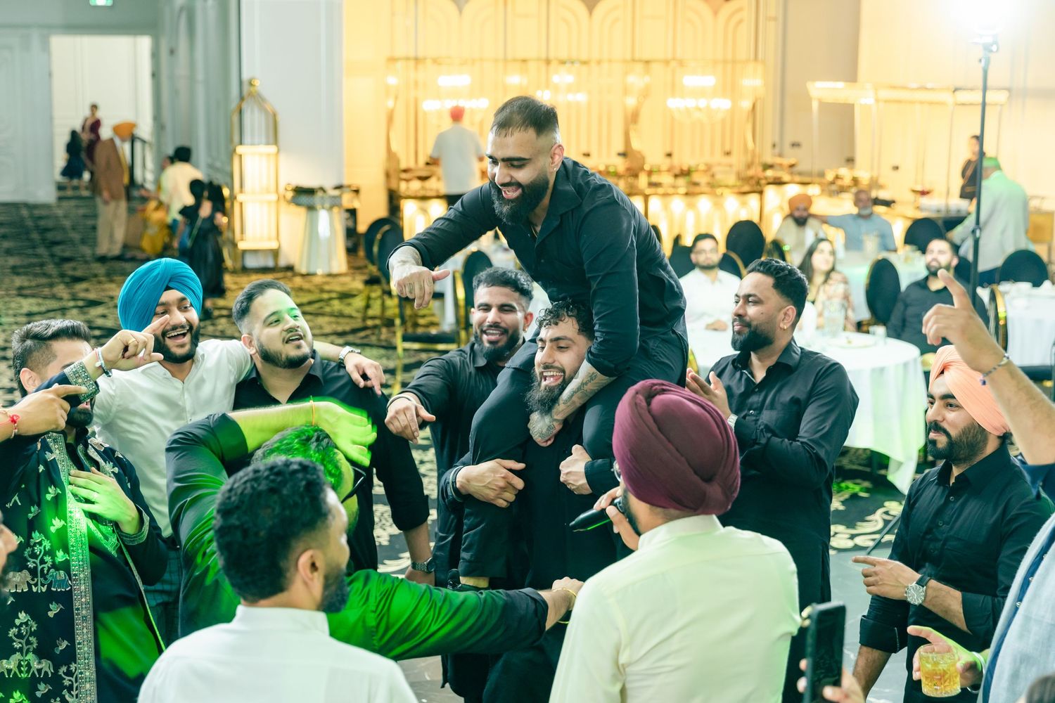 Group of people gathered in a crowd having animated conversations at an indoor event.