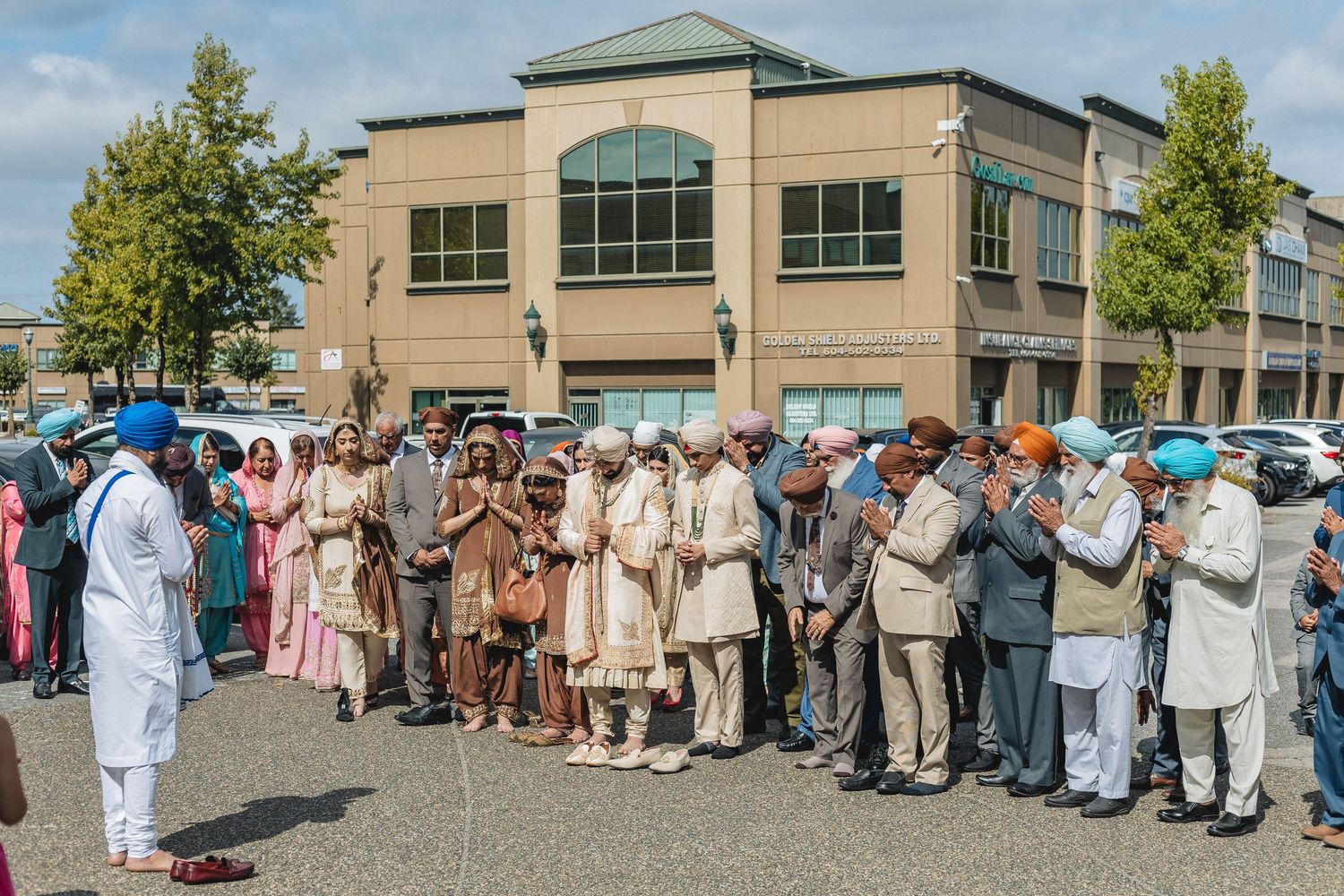 Large group of wedding guests in traditional attire gathered outside a building.