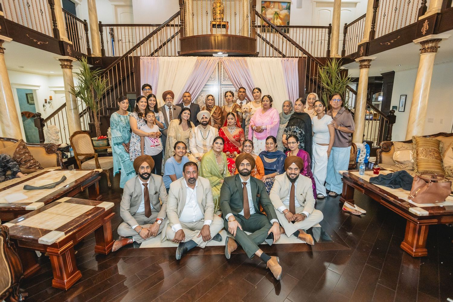 Large group photo of wedding guests gathered on indoor staircase.