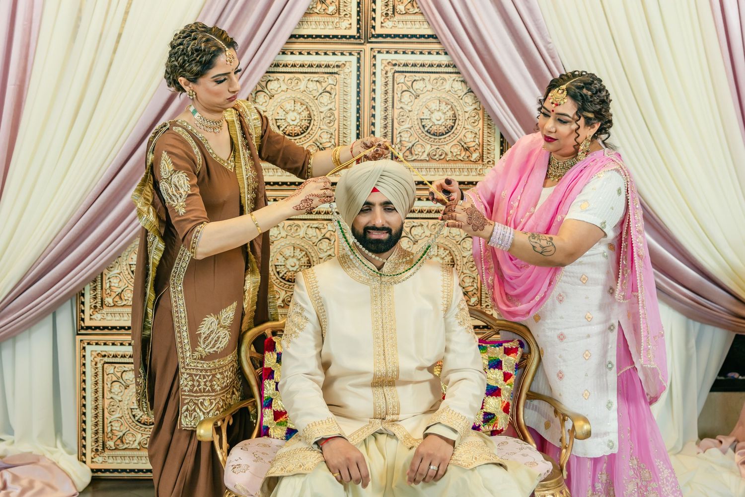 Wedding ceremony setup with elegant white and pink drapes, ornate gold decor, and traditional decorative elements.