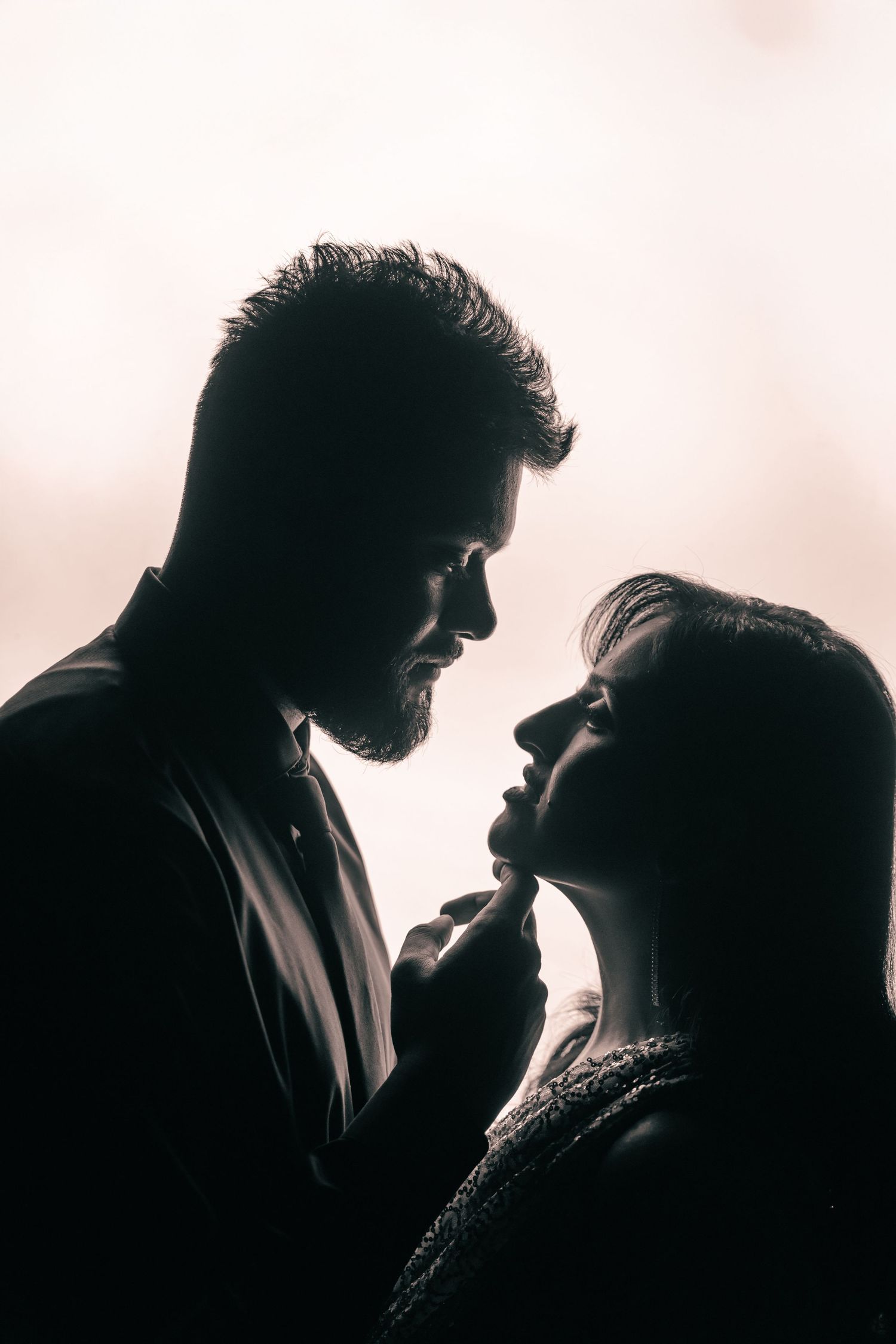 Dramatic silhouette portraits capture an intimate moment against a light background.