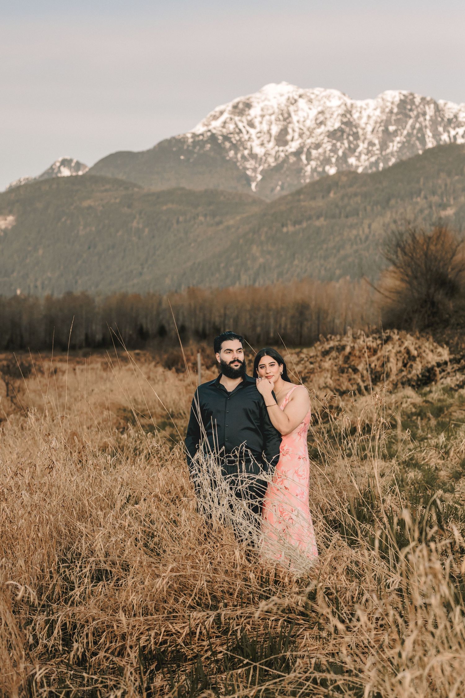 Romantic outdoor portrait session with mountains and dried grass creating a warm, natural setting.