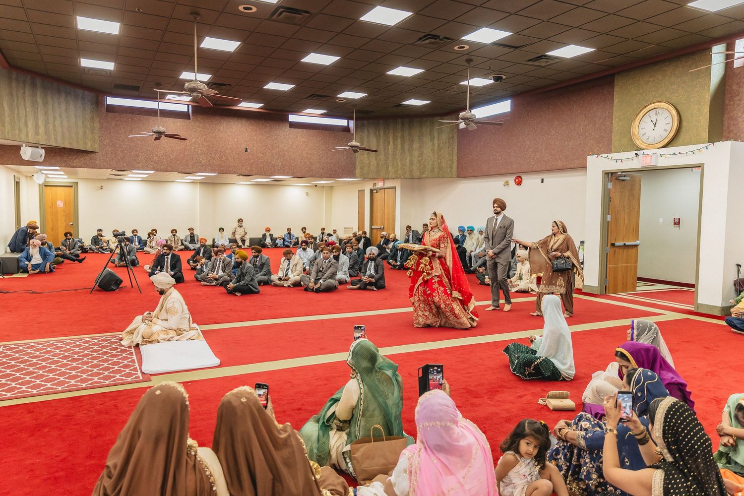 Wide view of wedding ceremony space with red carpet and guests seated in rows.