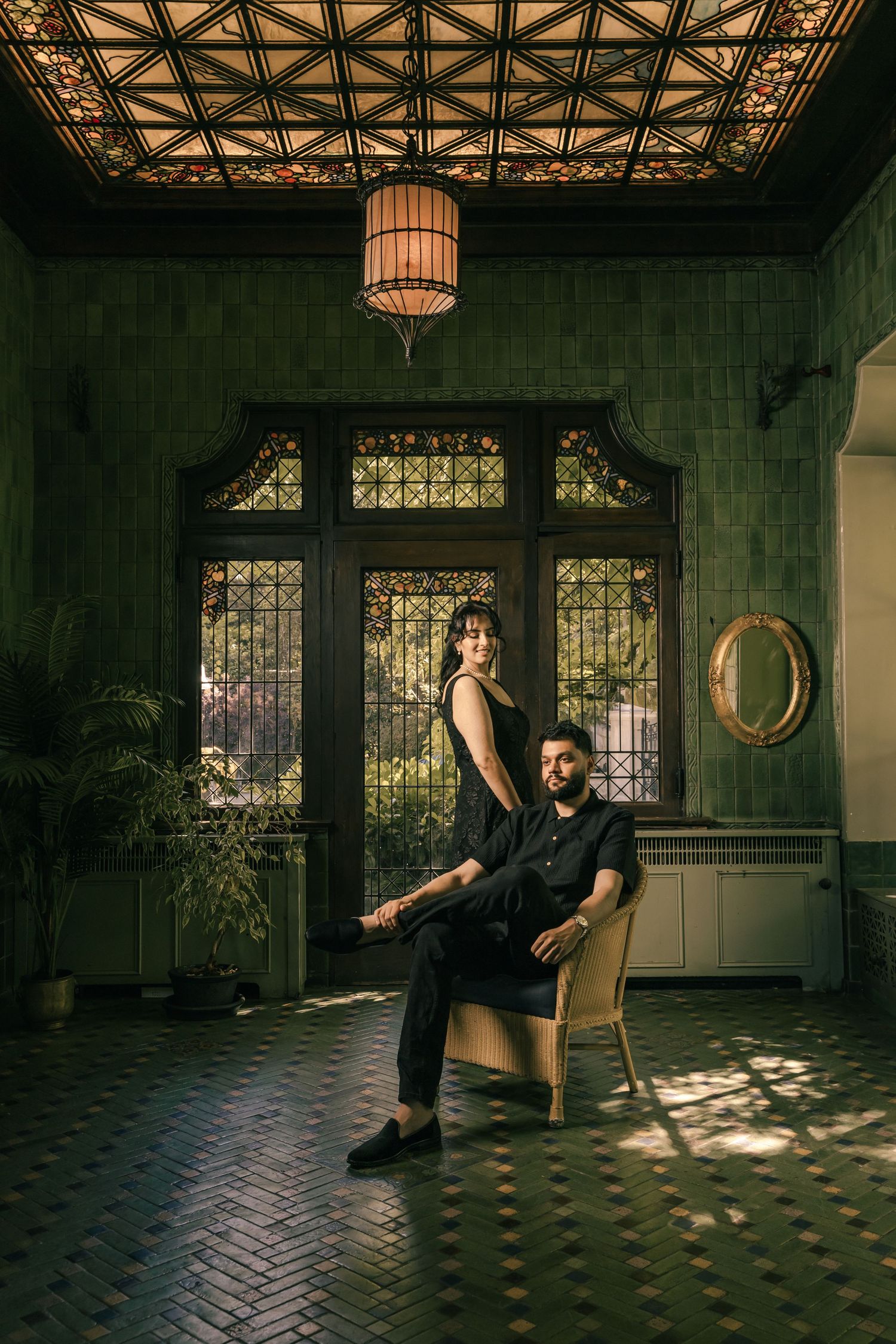 An elegant indoor photoshoot featuring a vintage chair and ornate ceiling with moody lighting.
