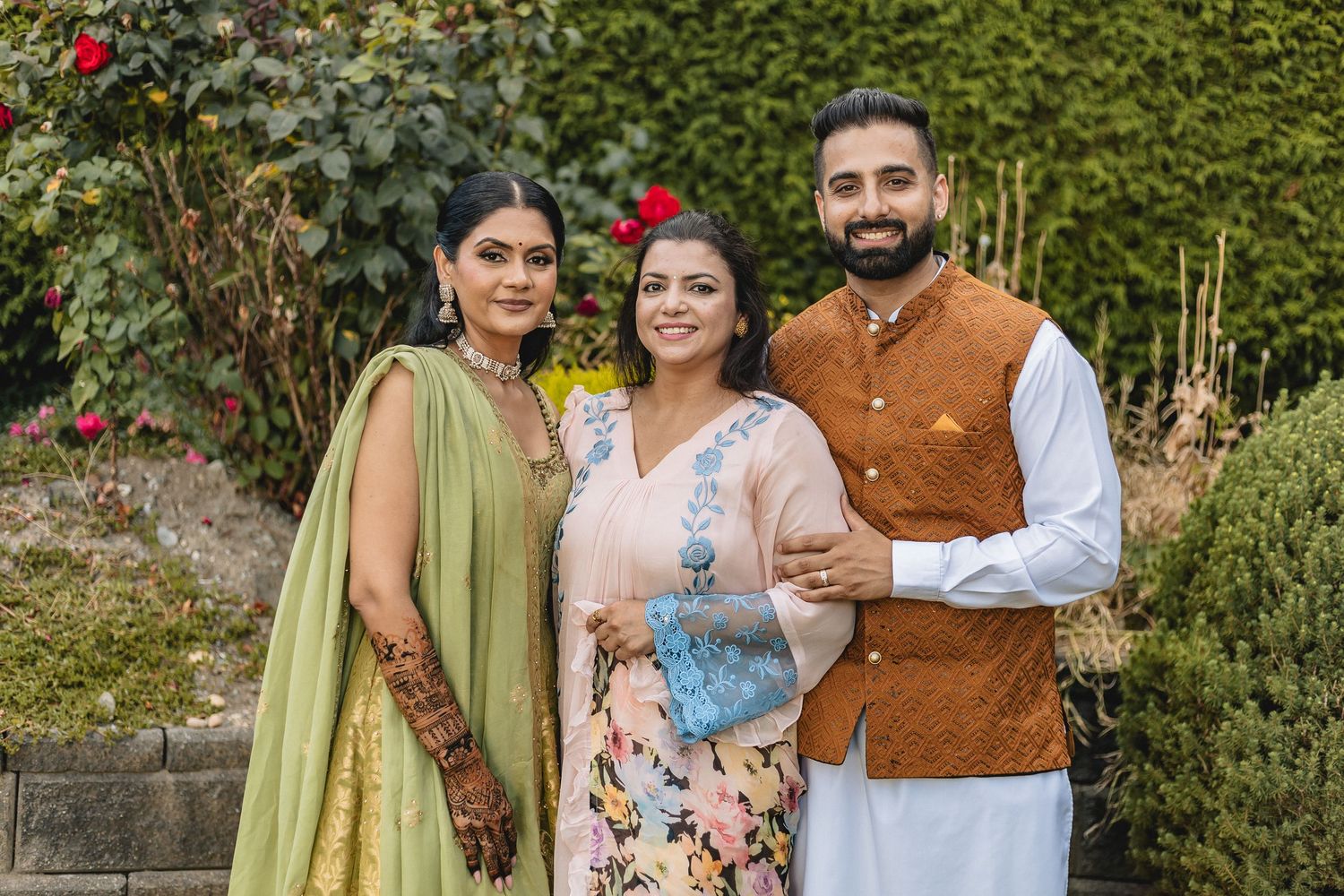 Friends in festive ethnic wear share joyful moments in a garden setting.