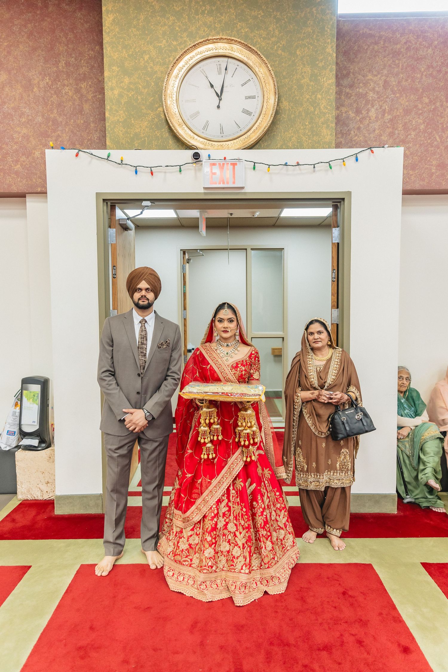 Traditional Indian wedding ceremony in a temple hall with red carpet and ornate decorations.