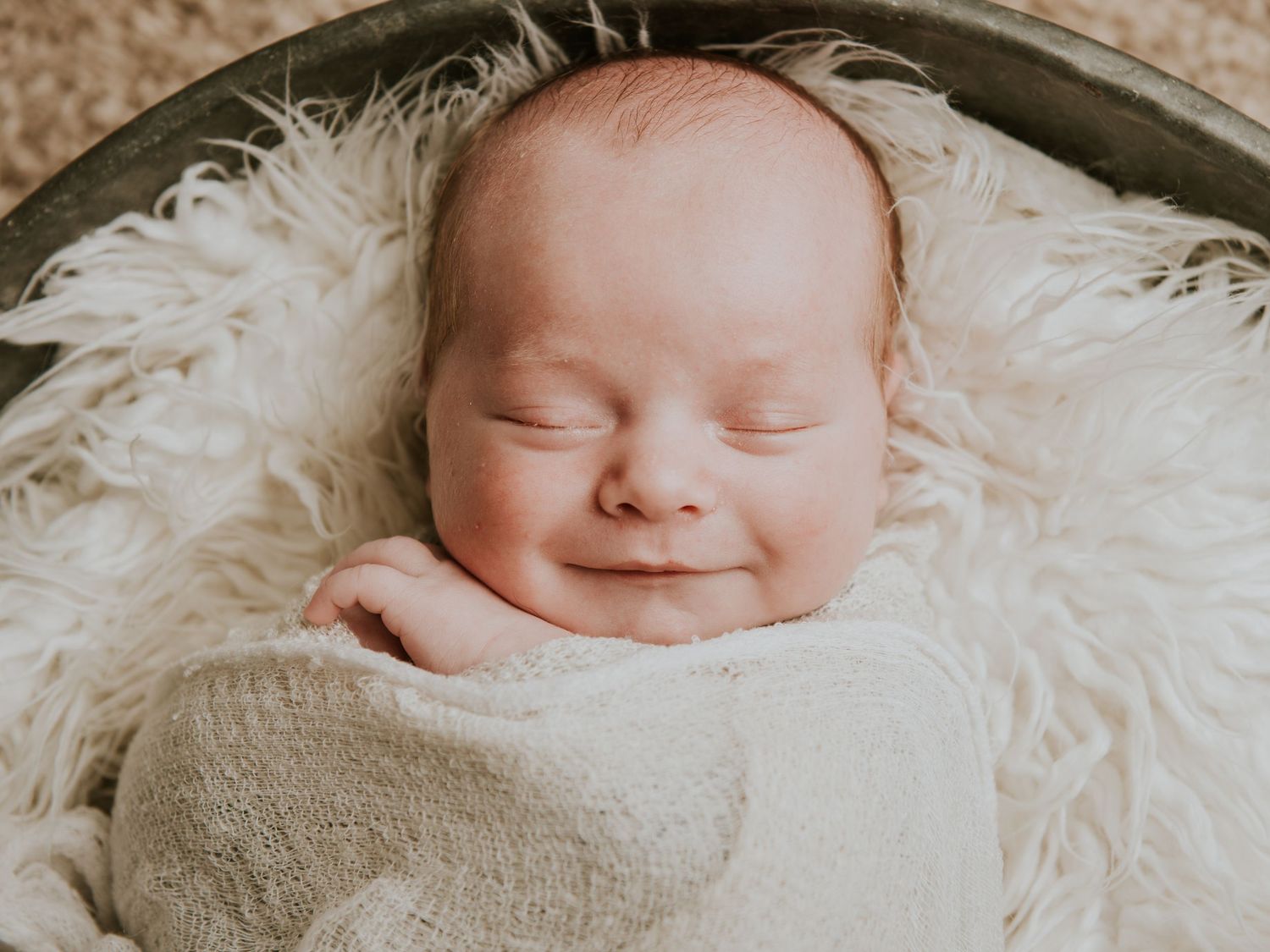 Peaceful newborn baby sleeping on soft white fur blanket.