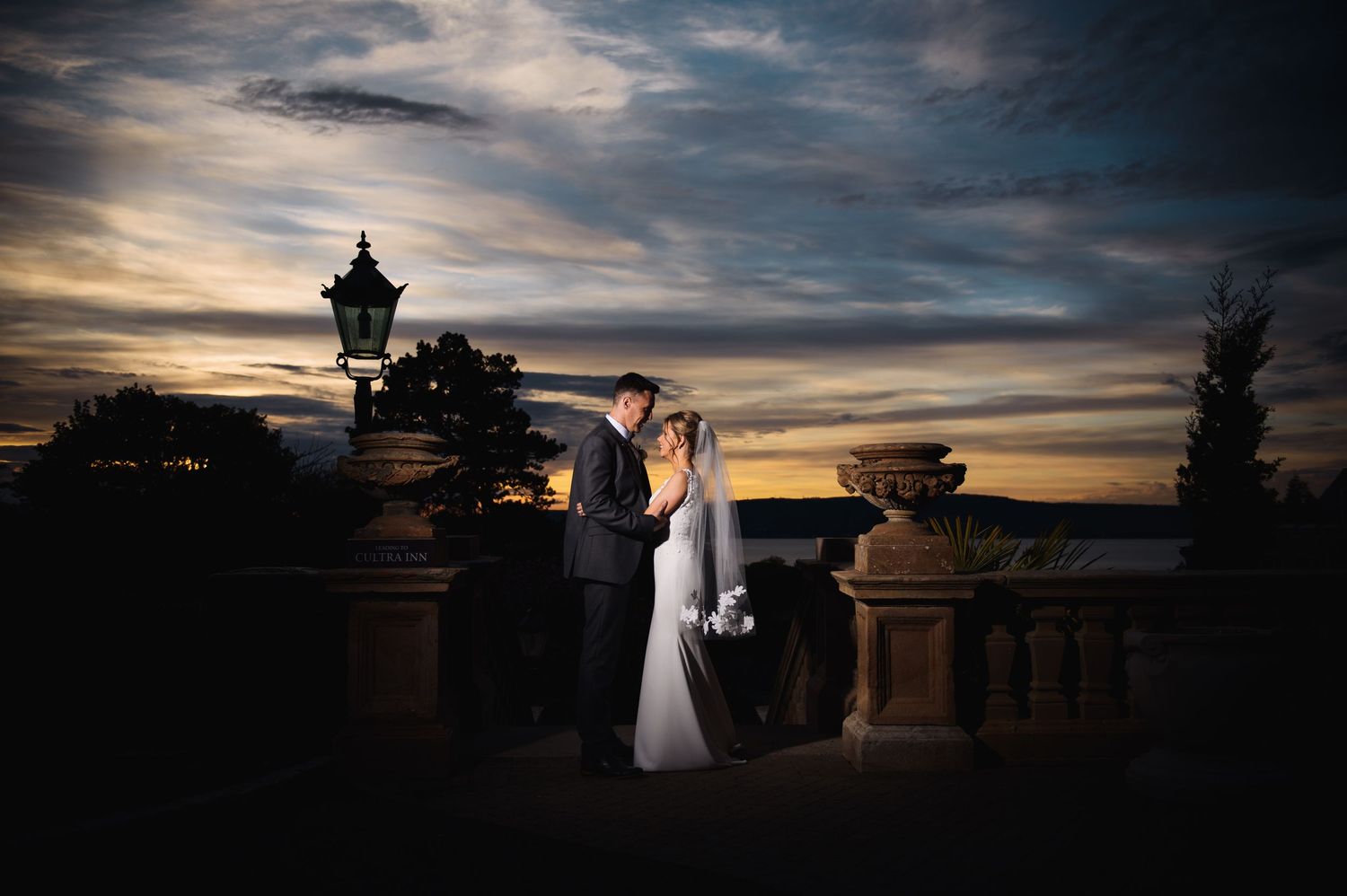 Dramatic sunset silhouettes of wedding couple against ornate architecture.