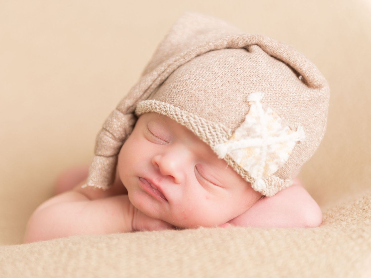 Sleeping newborn baby wrapped in delicate beige fabric.