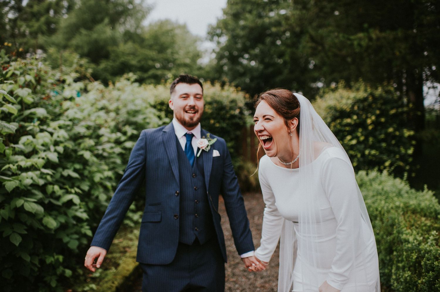 A couple shares joyful moments in a lush garden setting during their wedding celebration.