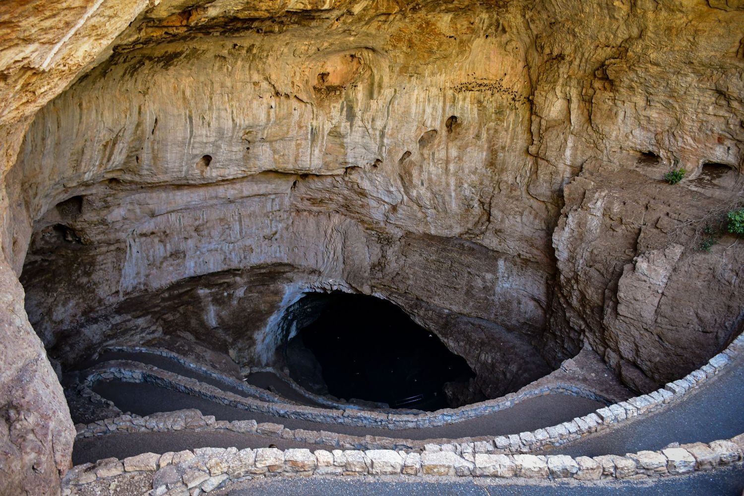 A natural cave entrance with limestone formations and dark depths visible.
