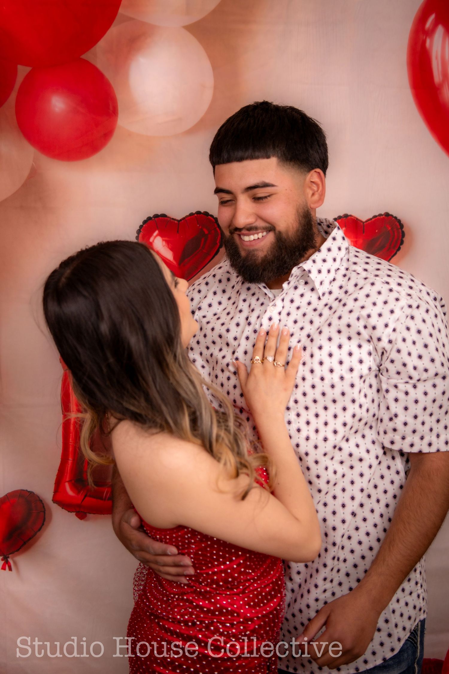 A romantic Valentine's Day photo session with red and pink balloons featuring a couple in polka dot and red outfits.