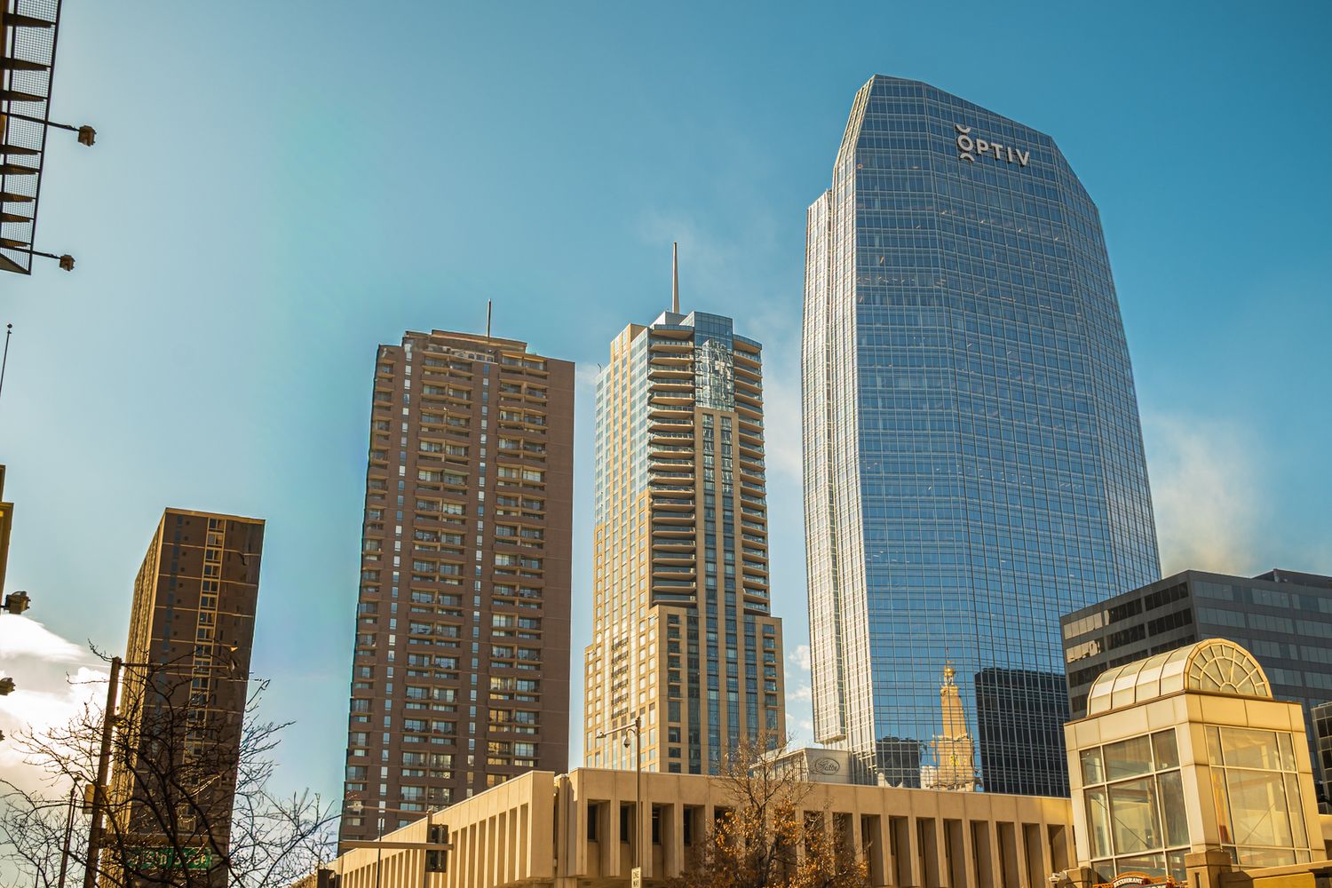 Modern skyscrapers and office buildings line the streets of downtown Los Angeles against a bright blue sky.
