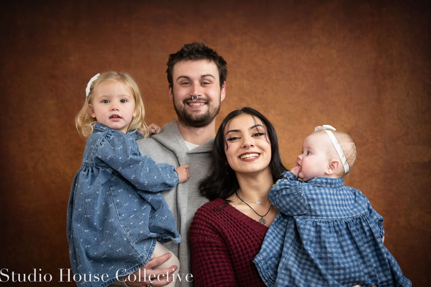 Family portrait session in studio against brown backdrop showing joyful expressions and coordinated casual outfits.