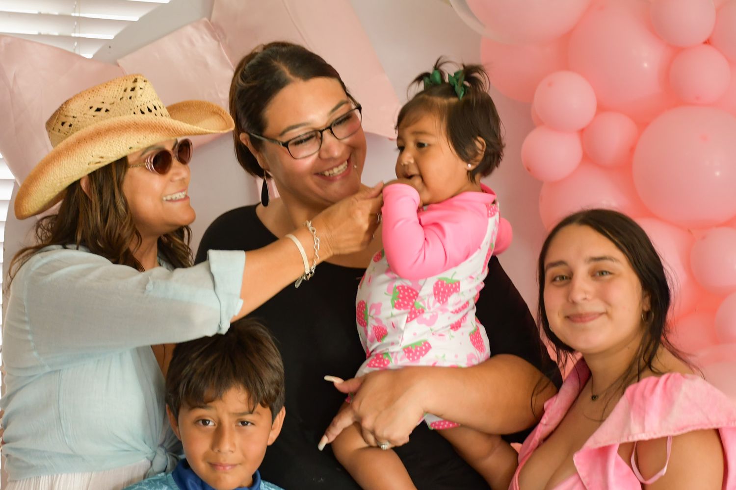 A family gathering with pink balloons in the background during a celebration.