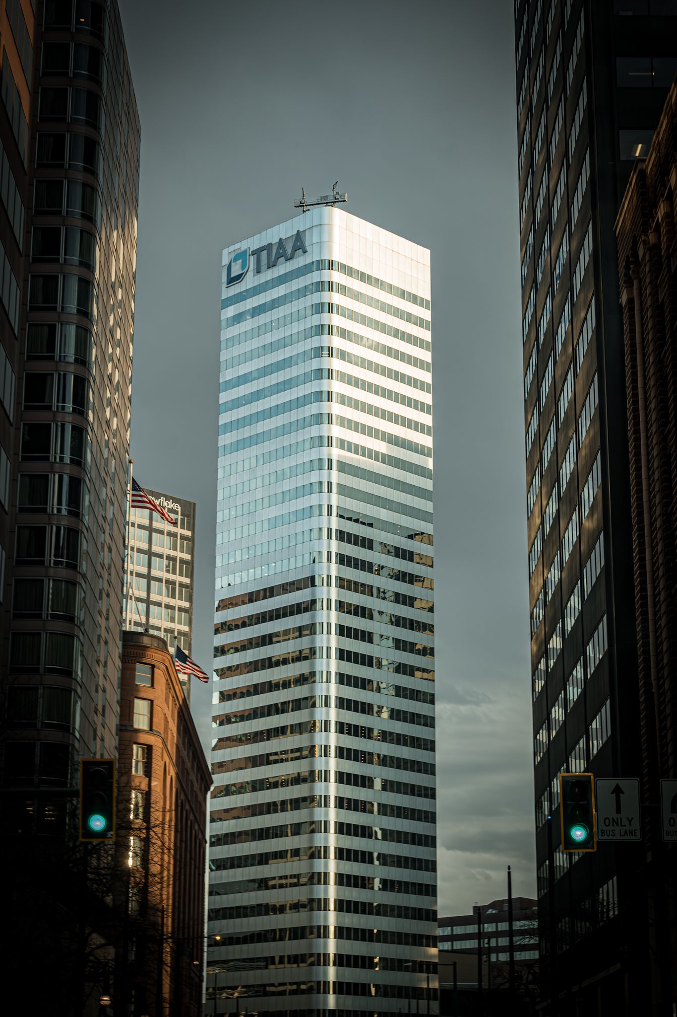 Modern glass skyscraper with CIBC logo towers between city buildings under dramatic cloudy sky in urban setting.