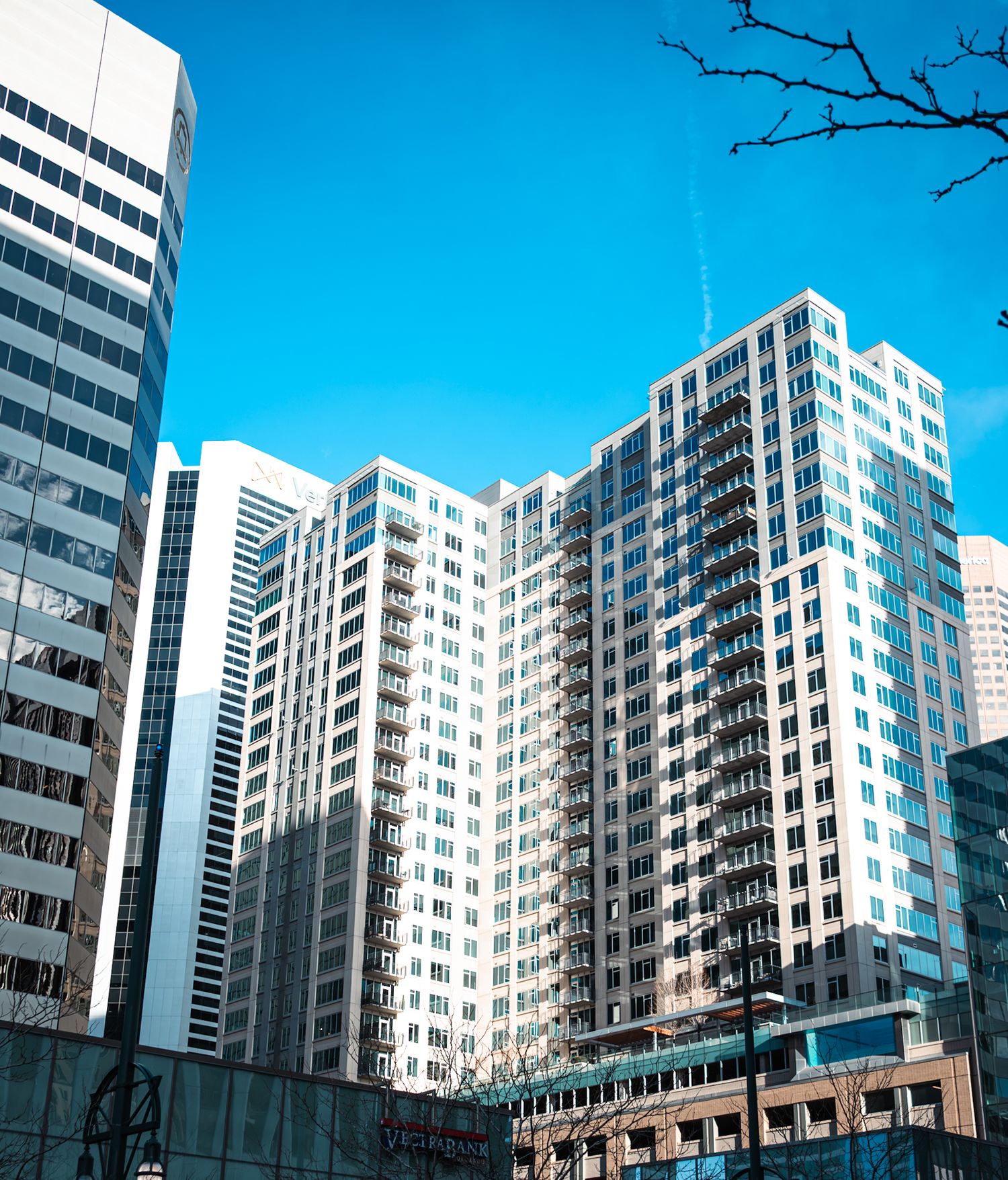 Modern high-rise apartment buildings with white facades against bright blue sky in urban setting.