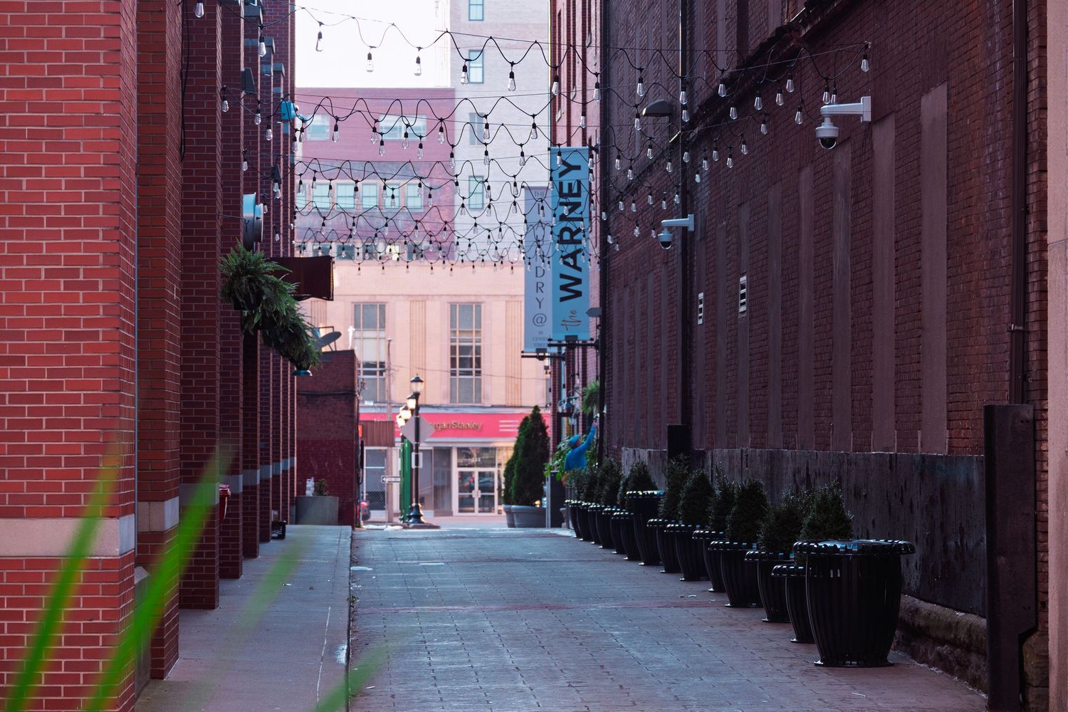 Red brick alleyway decorated with string lights and bunting creating a festive atmosphere.