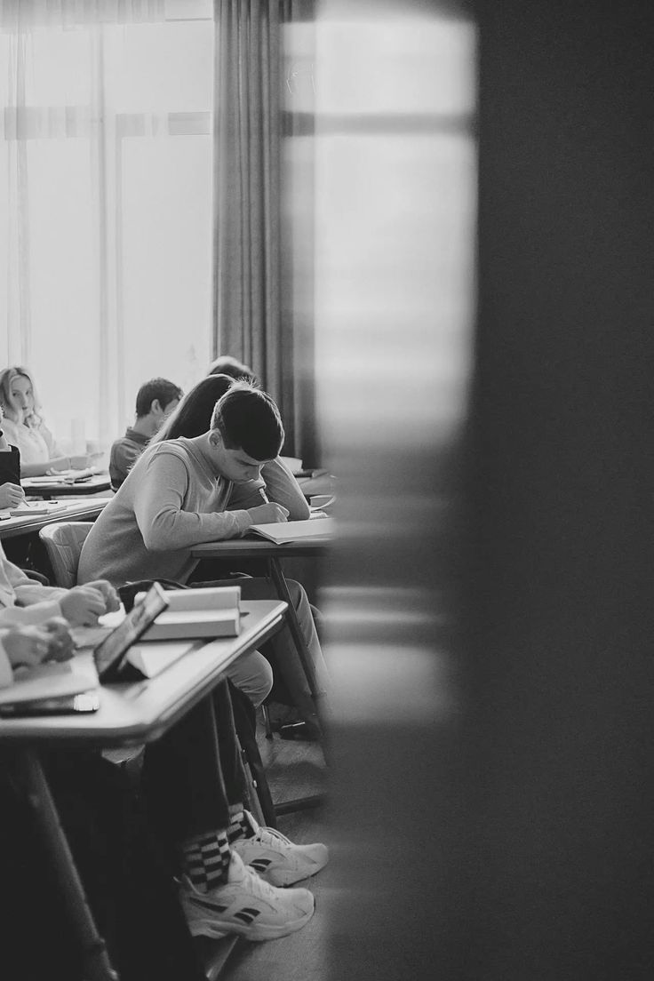 Black and white photo of students studying at desks in a classroom.