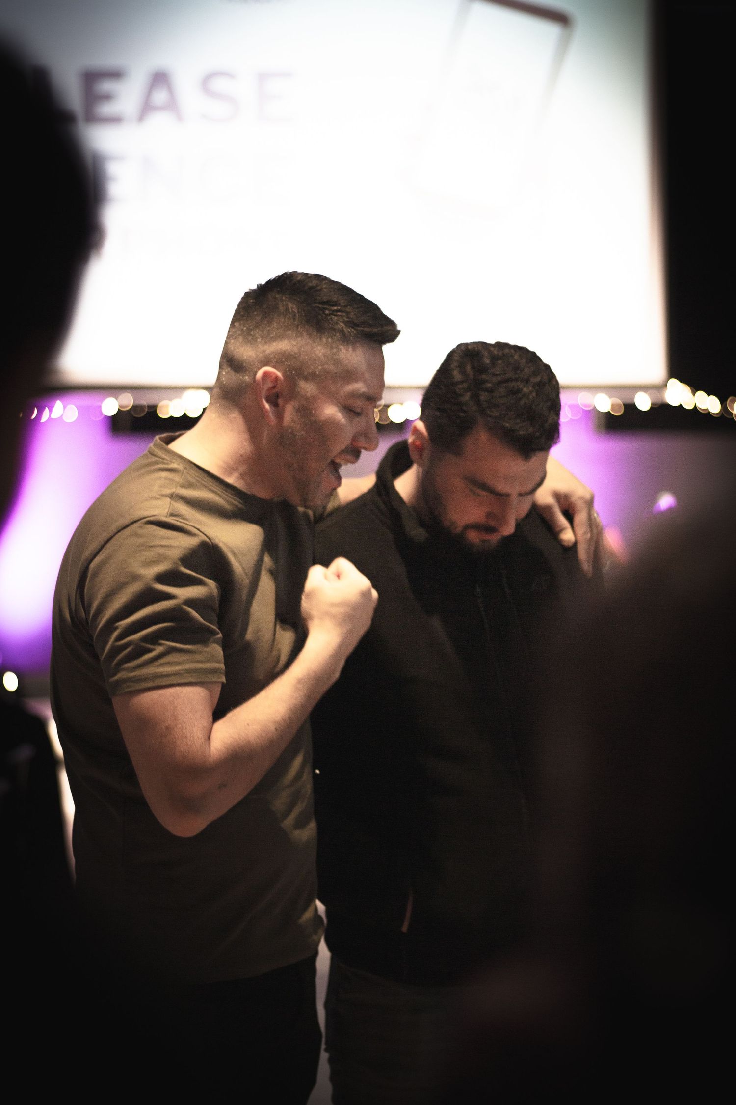 A male pastor praying over another man.