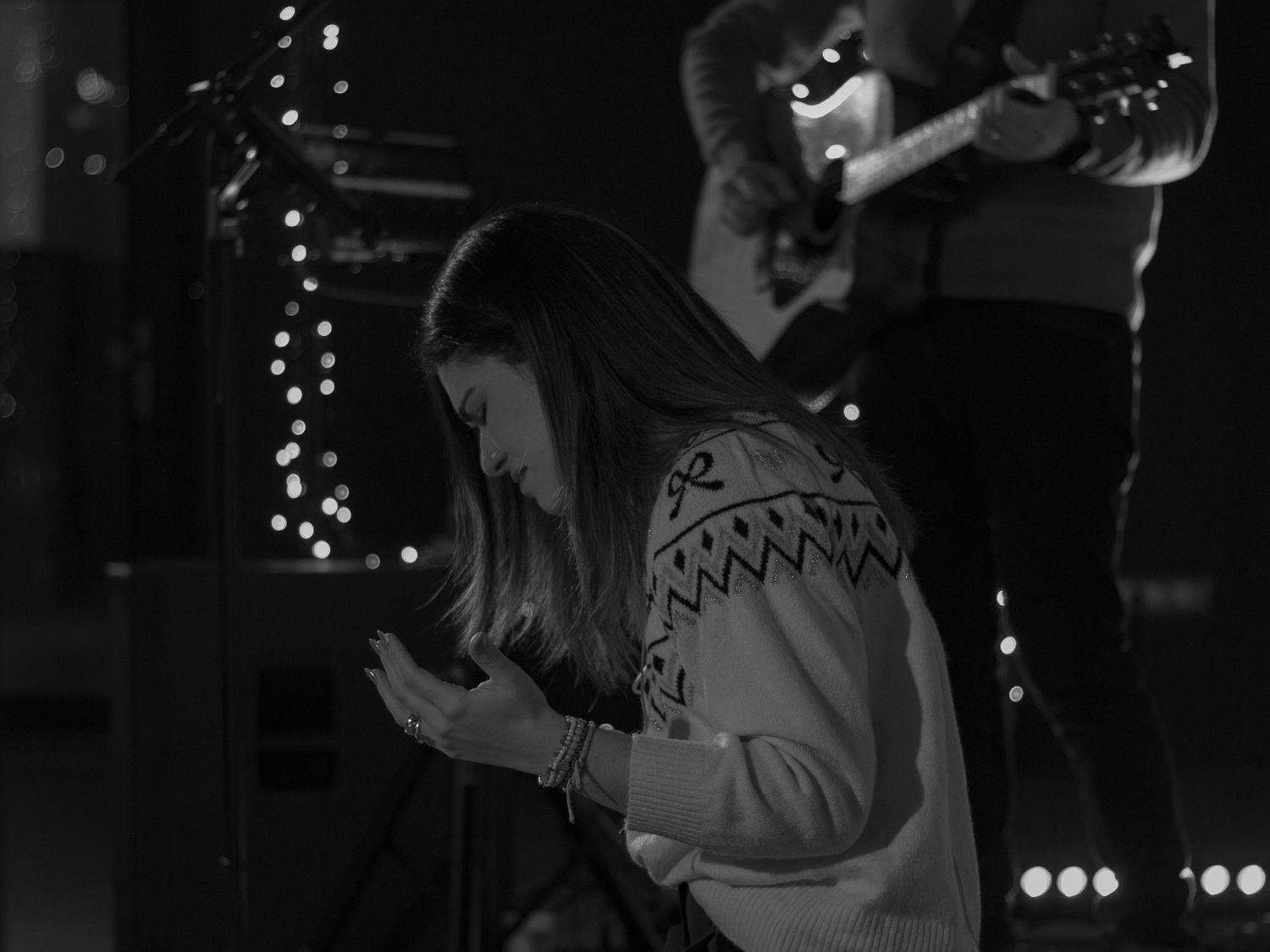 Black and White image of an emotional woman worshipping God on her knees.
