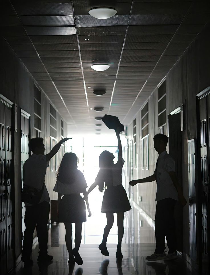 Silhouettes of students celebrating in a bright school hallway, tossing graduation caps.
